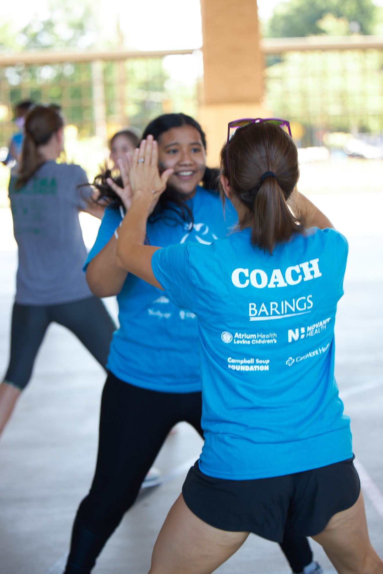 Two girls in yellow Girls on the Run shirts embrace with smiles